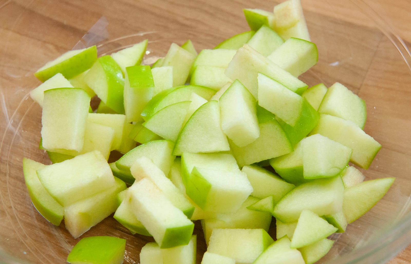 Small even cubes of peeled apple spread across a cutting board.