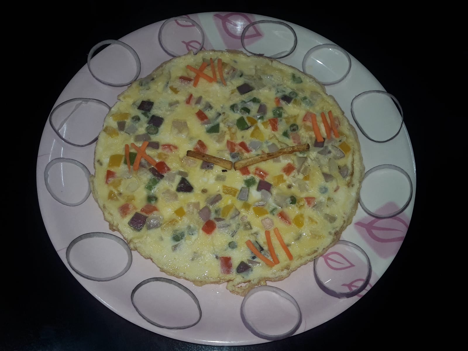 An open omelet flecked with diced red, yellow, and green bell peppers on a white plate.