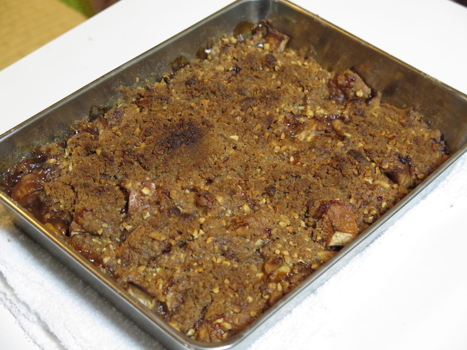 A freshly baked apple crisp in a rectangular metal pan with browned crumb and bubbling fruit at the edges.
