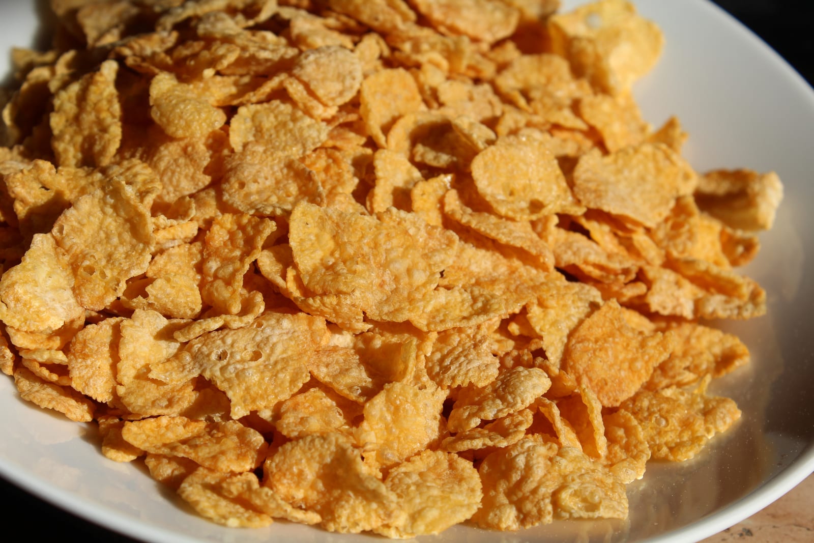 Plain golden cornflakes piled in a wide white bowl.