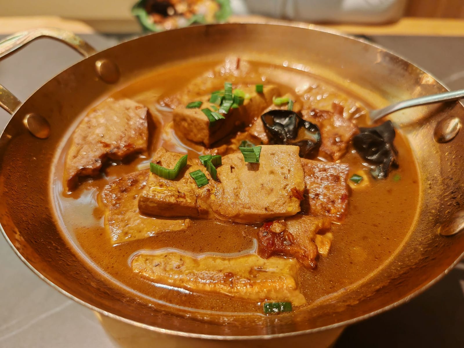 Golden braised tofu and black mushrooms in a warm brown sauce, finished with sliced scallions.