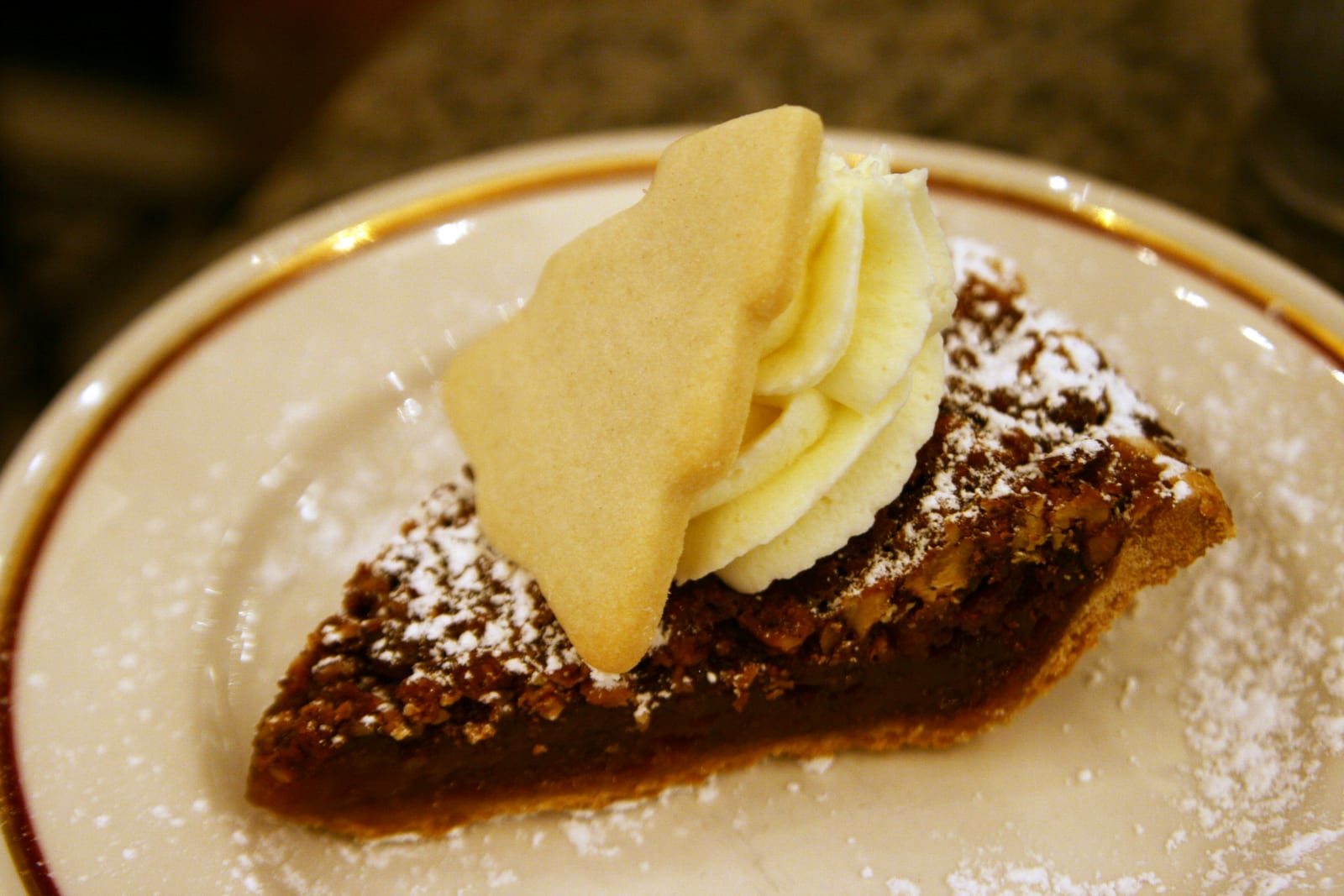 A restaurant slice of pecan pie on a white plate.