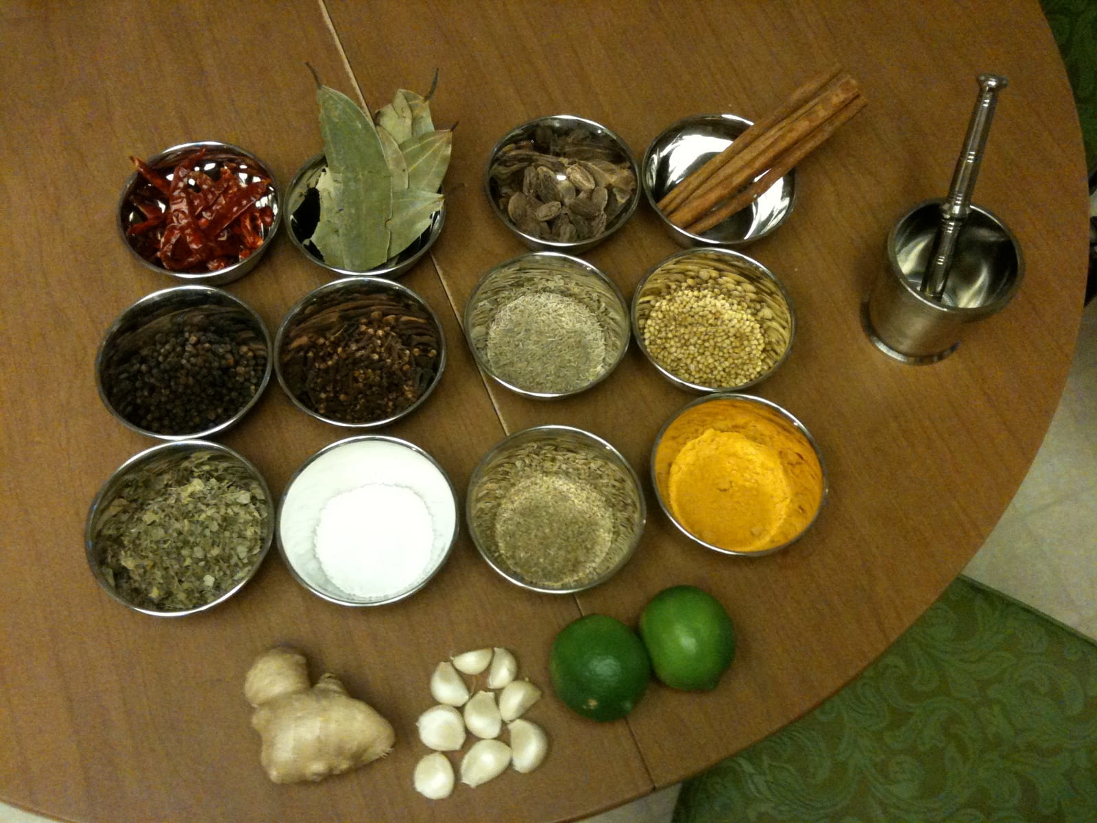 Ginger, garlic, turmeric, cumin, chiles, cinnamon, cardamom, and other butter chicken spices arranged on a table.
