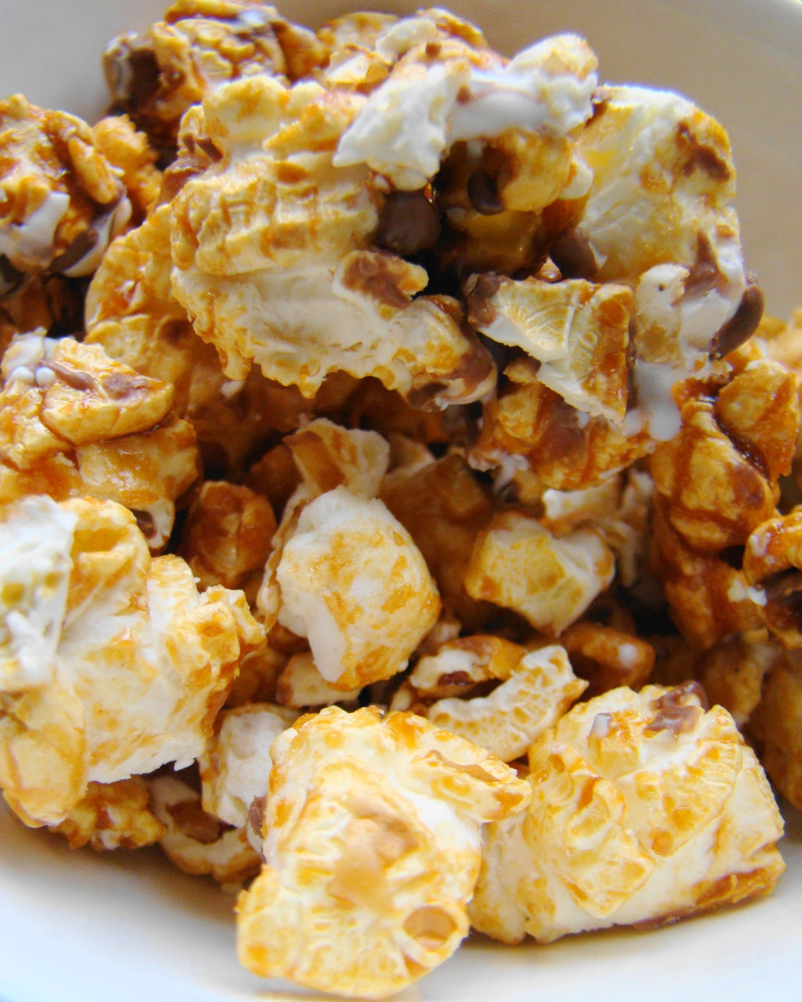 Close view of caramel-coated popcorn with amber sugar gathered around the kernels.