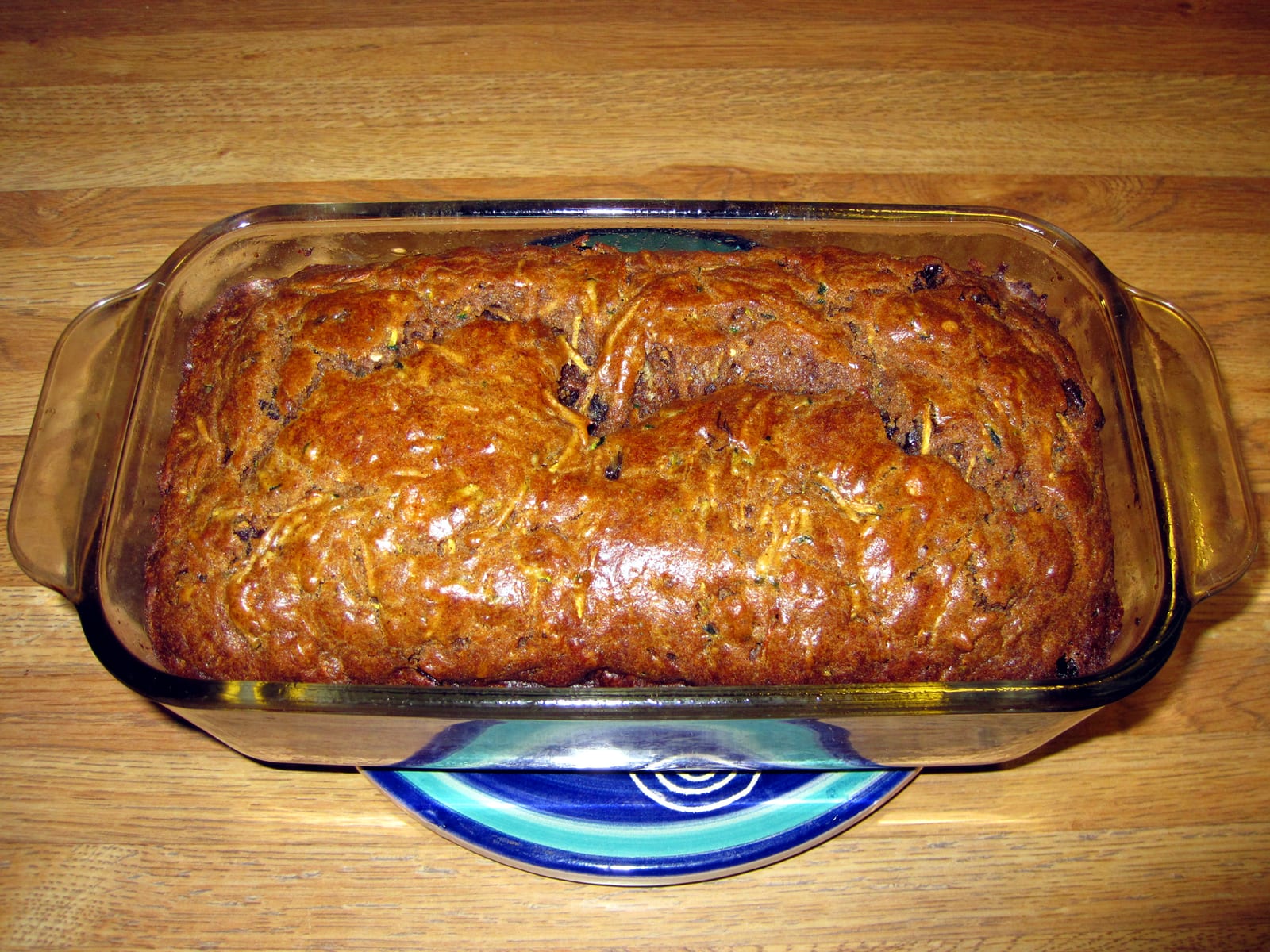 A browned apple zucchini quick bread baked in a glass loaf pan.