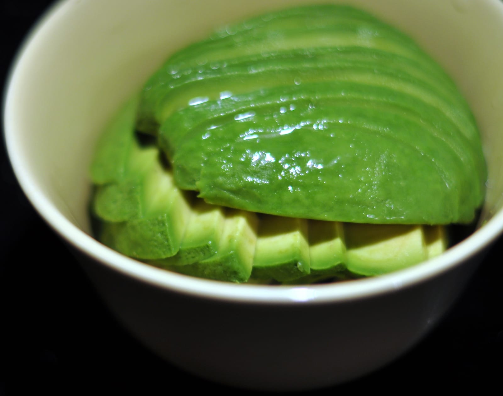 A ripe avocado half sliced into a neat fan inside a bowl.