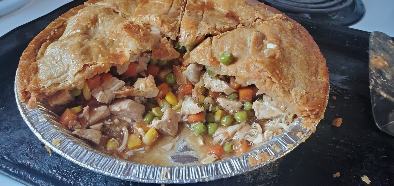 A round chicken pot pie opened to show chicken, peas, carrots, and corn.