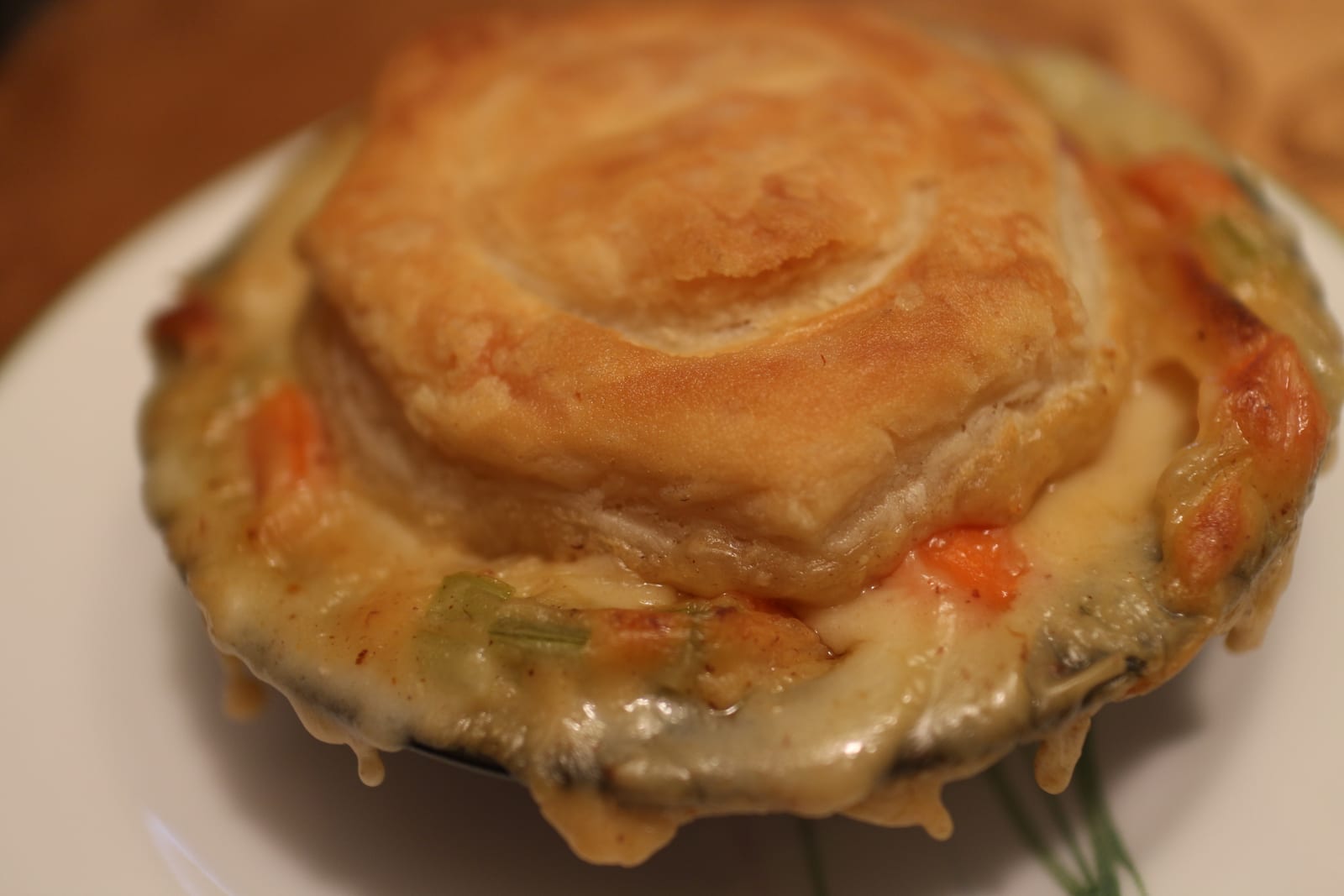 An individual chicken pot pie with a browned biscuit-like top and creamy vegetables at the rim.