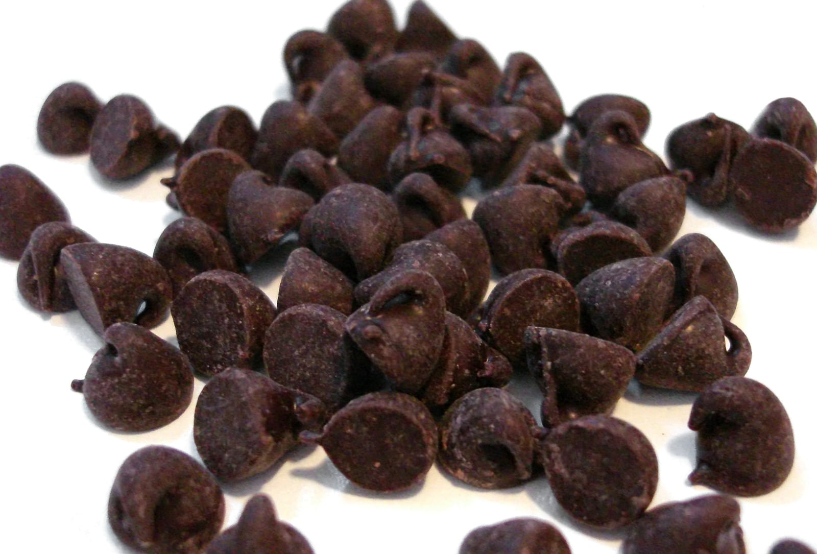 Semisweet chocolate chips scattered across a white surface.