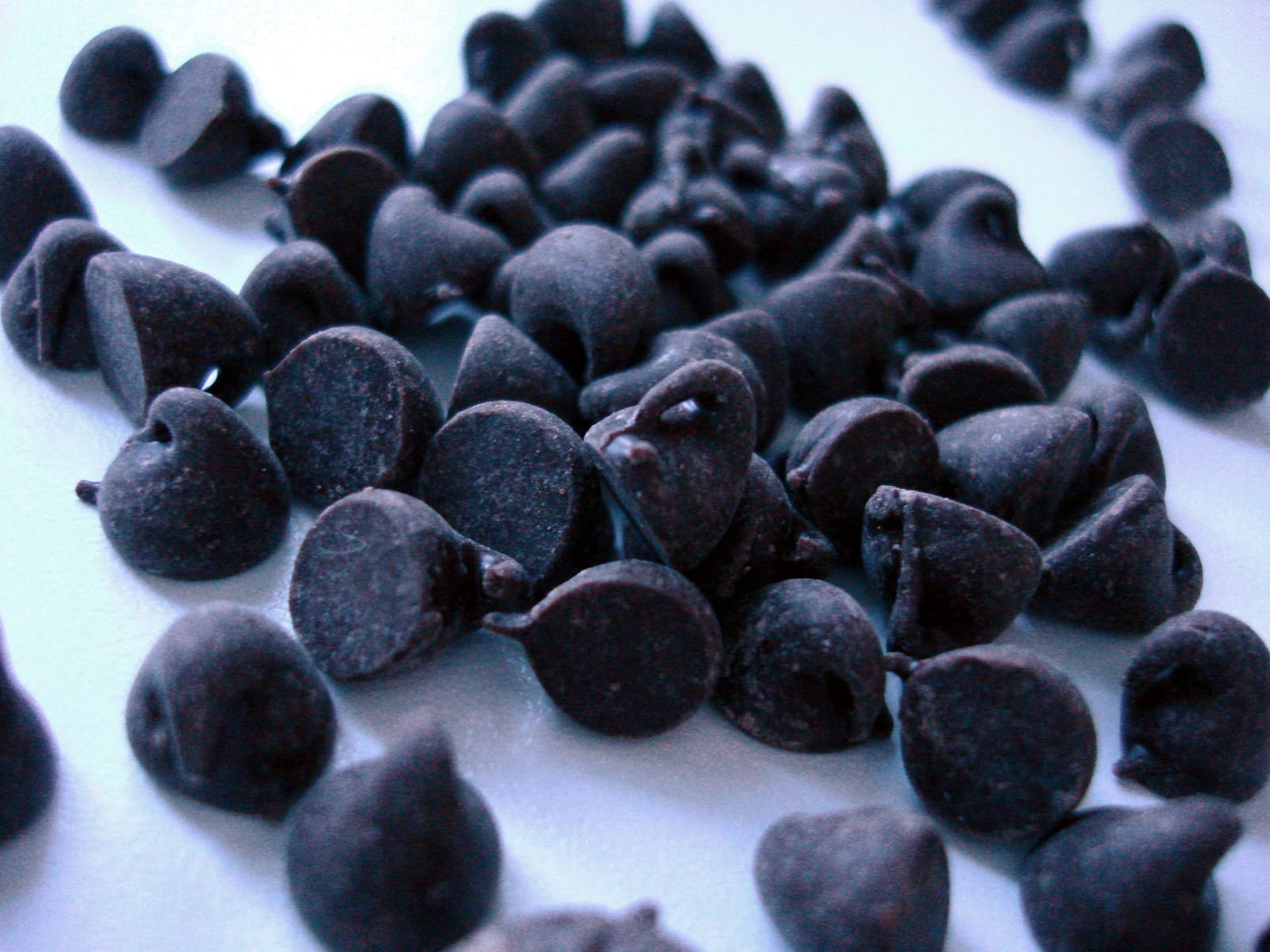 Semi-sweet chocolate chips scattered across a pale surface in a close view.