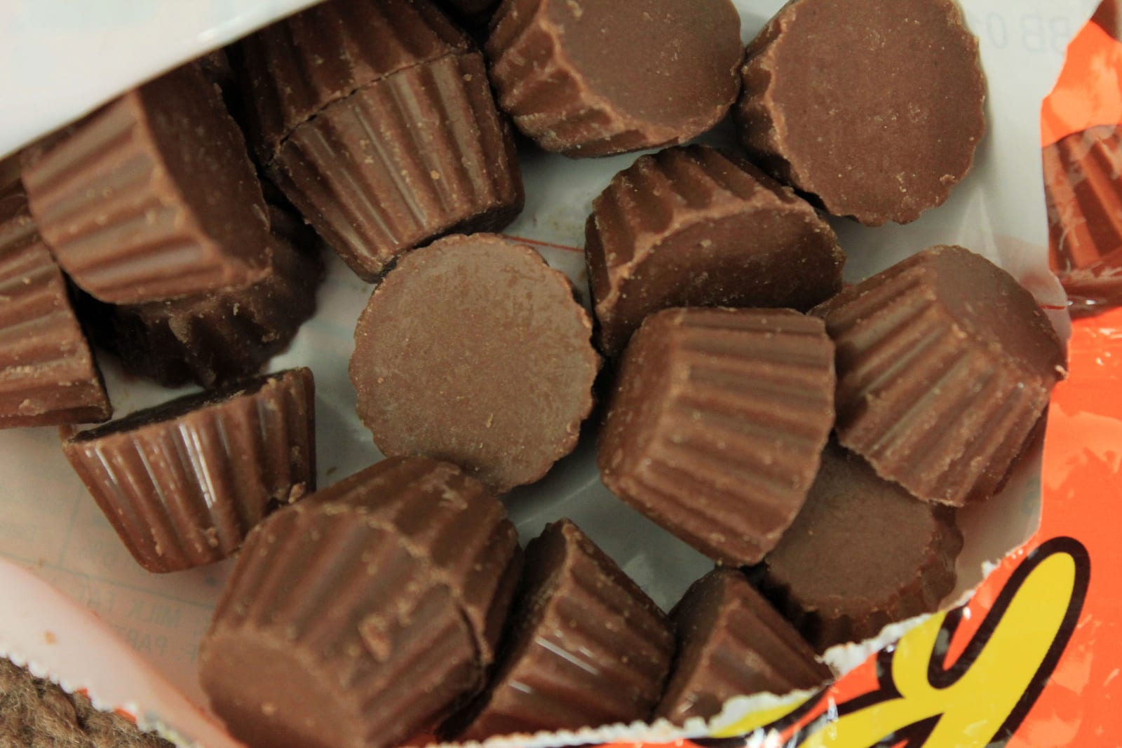 Unwrapped chocolate peanut butter cups arranged on a white plate.