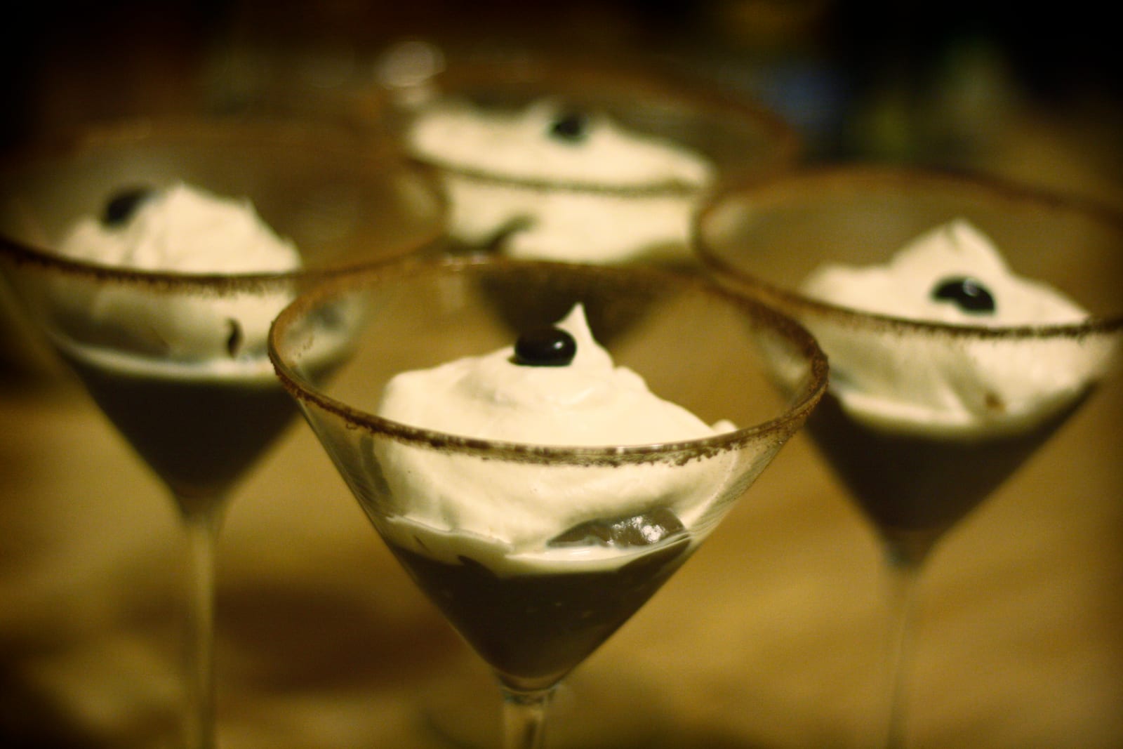 Three small glasses of dark chocolate pudding topped with whipped cream and chocolate shavings.