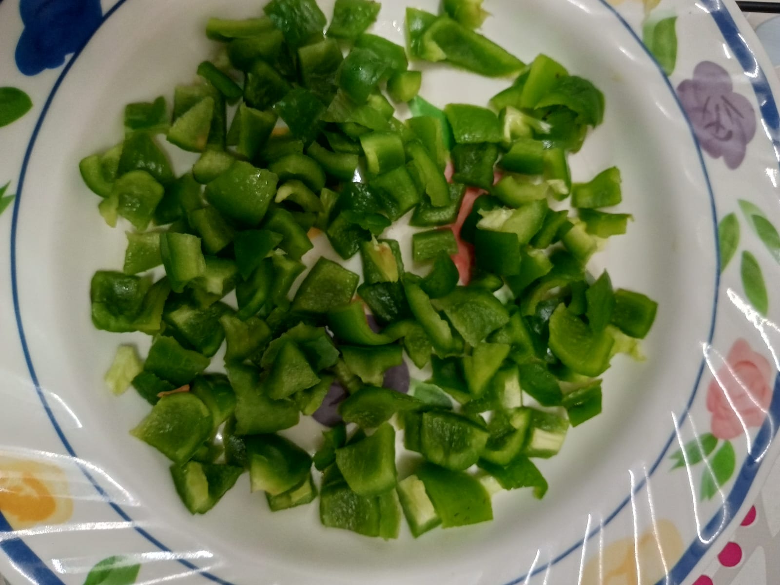Chopped green bell pepper spread across a patterned plate.