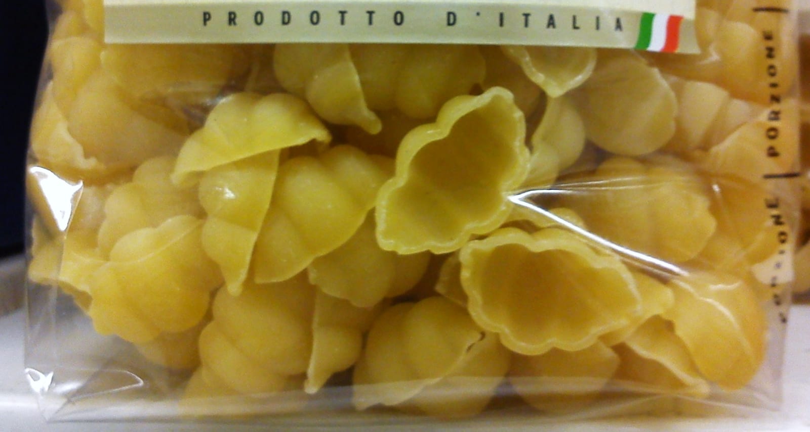 Dry conchiglie shell pasta visible through a clear package.