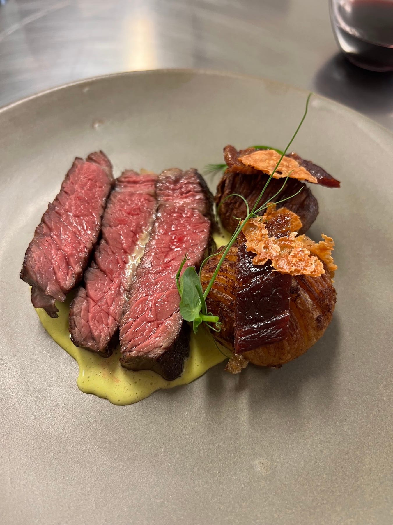 A plated meal with garlic Hasselback potatoes beside steak and sauce.