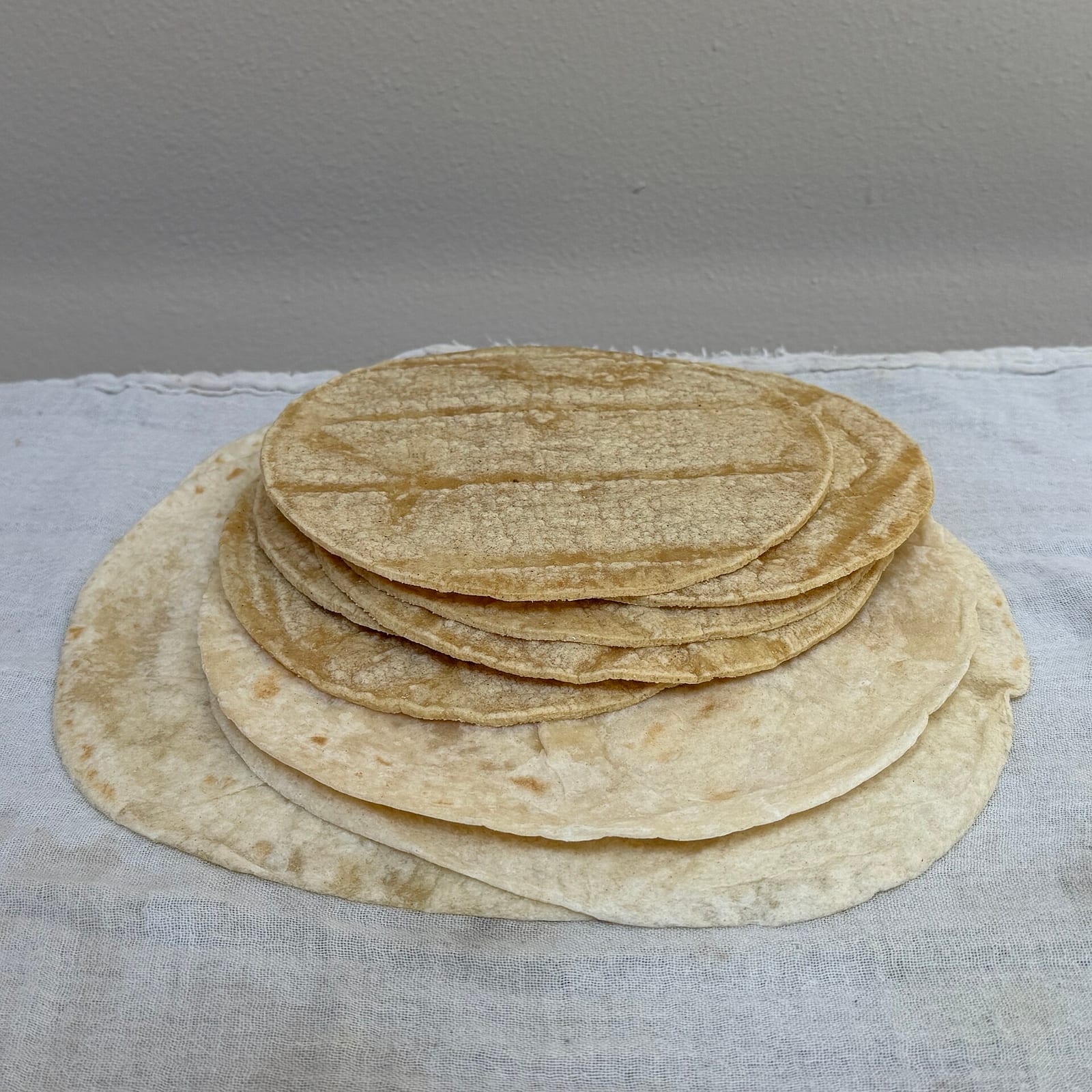 A stack of small corn tortillas resting on larger flour tortillas.