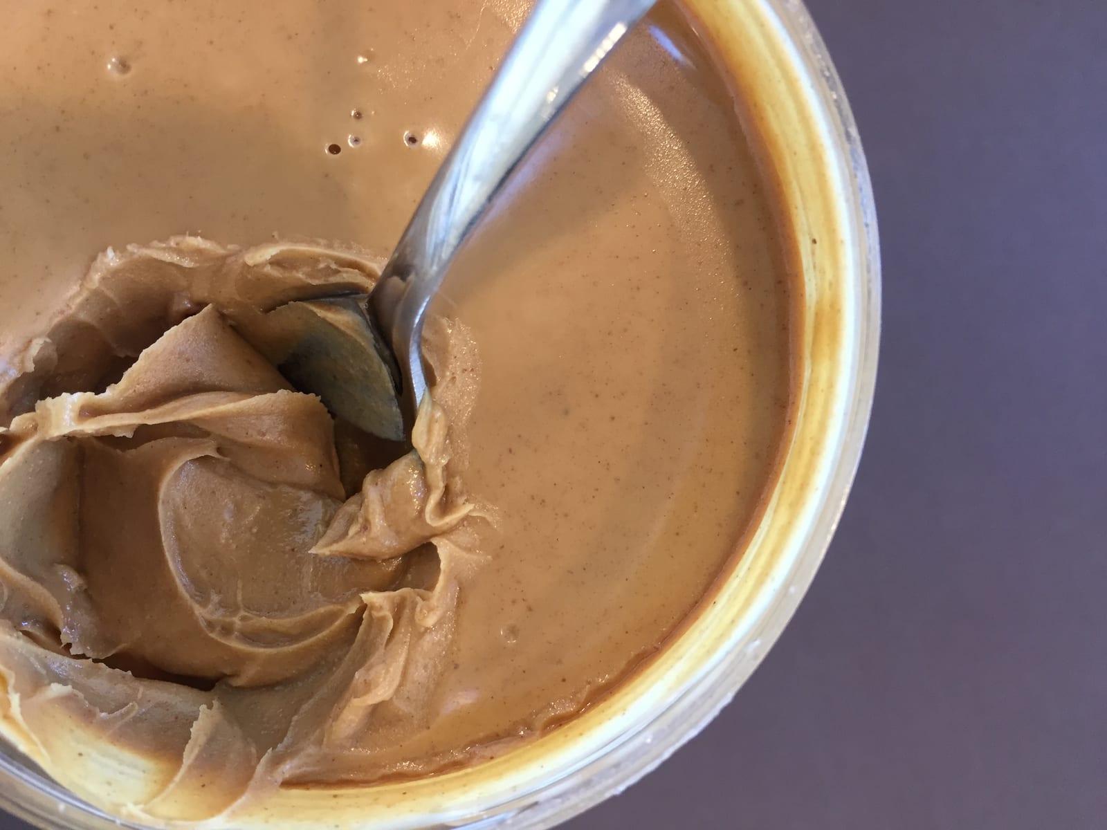 Creamy peanut butter in an open jar with a spoon.