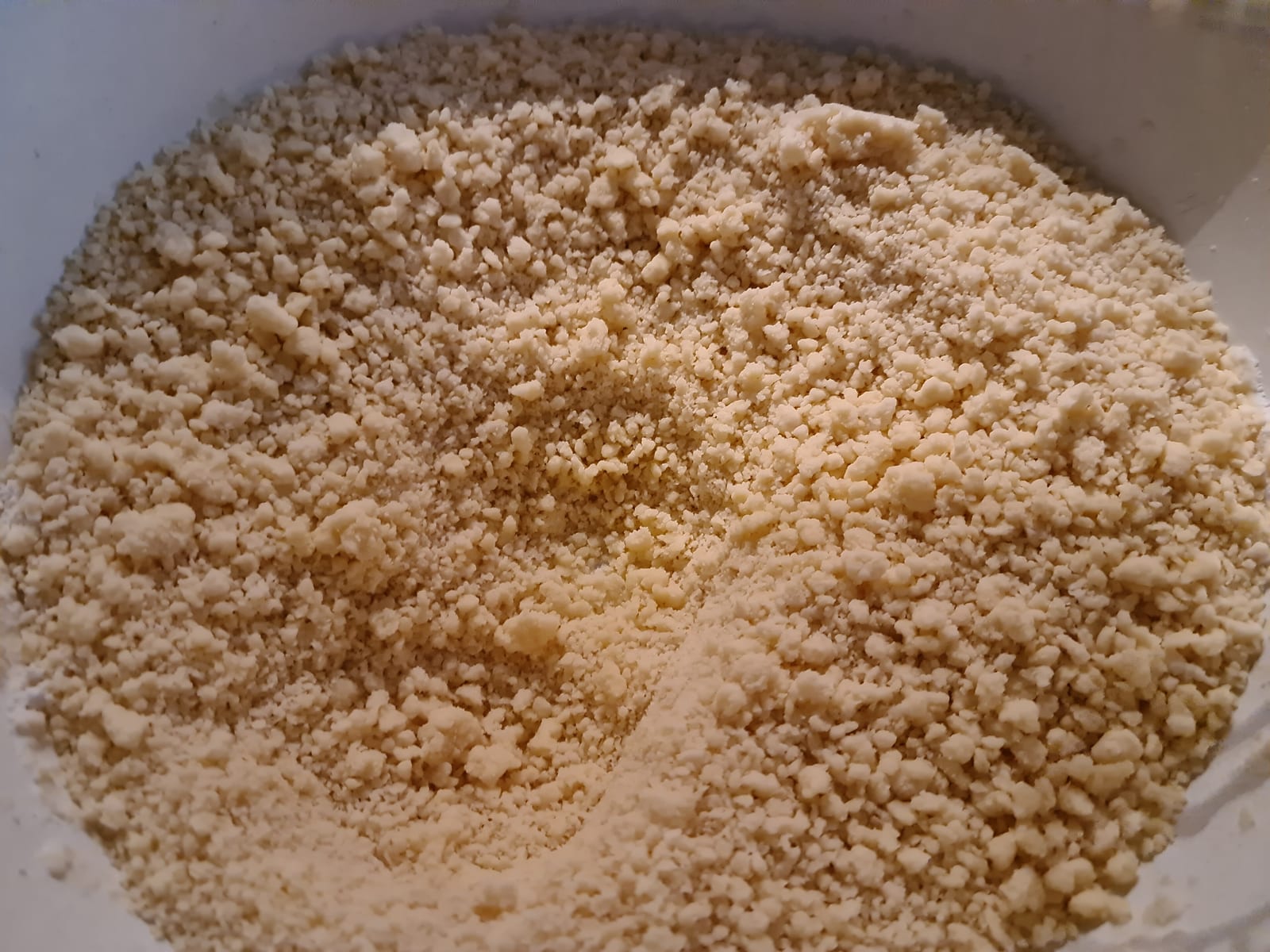 A close view of pale shortcrust crumbs in a mixing bowl.