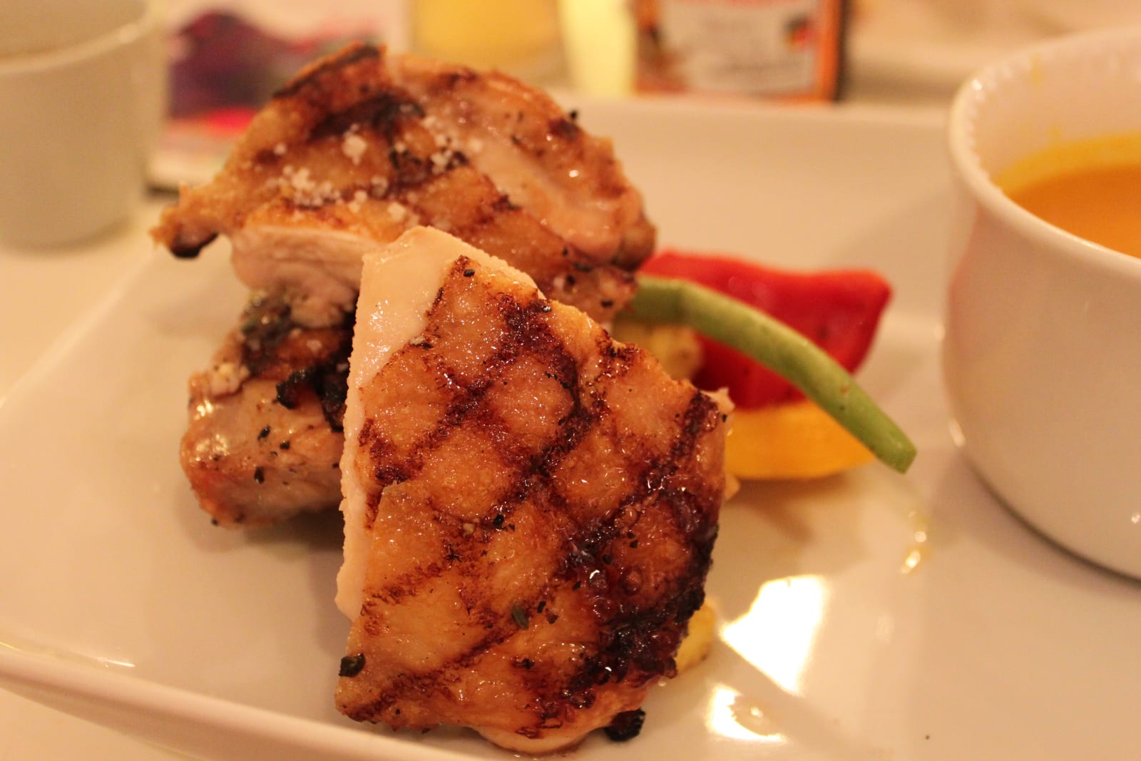 Plain grilled chicken pieces with dark grate marks arranged on a white plate.