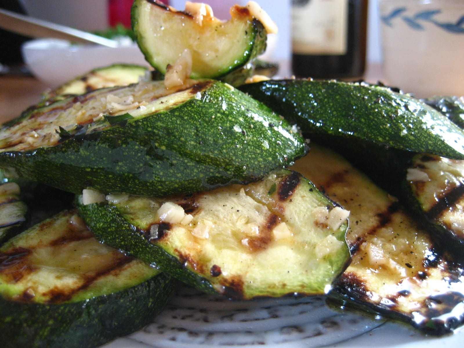 Close-up of thick zucchini slices with dark grill marks and a glossy herb dressing.