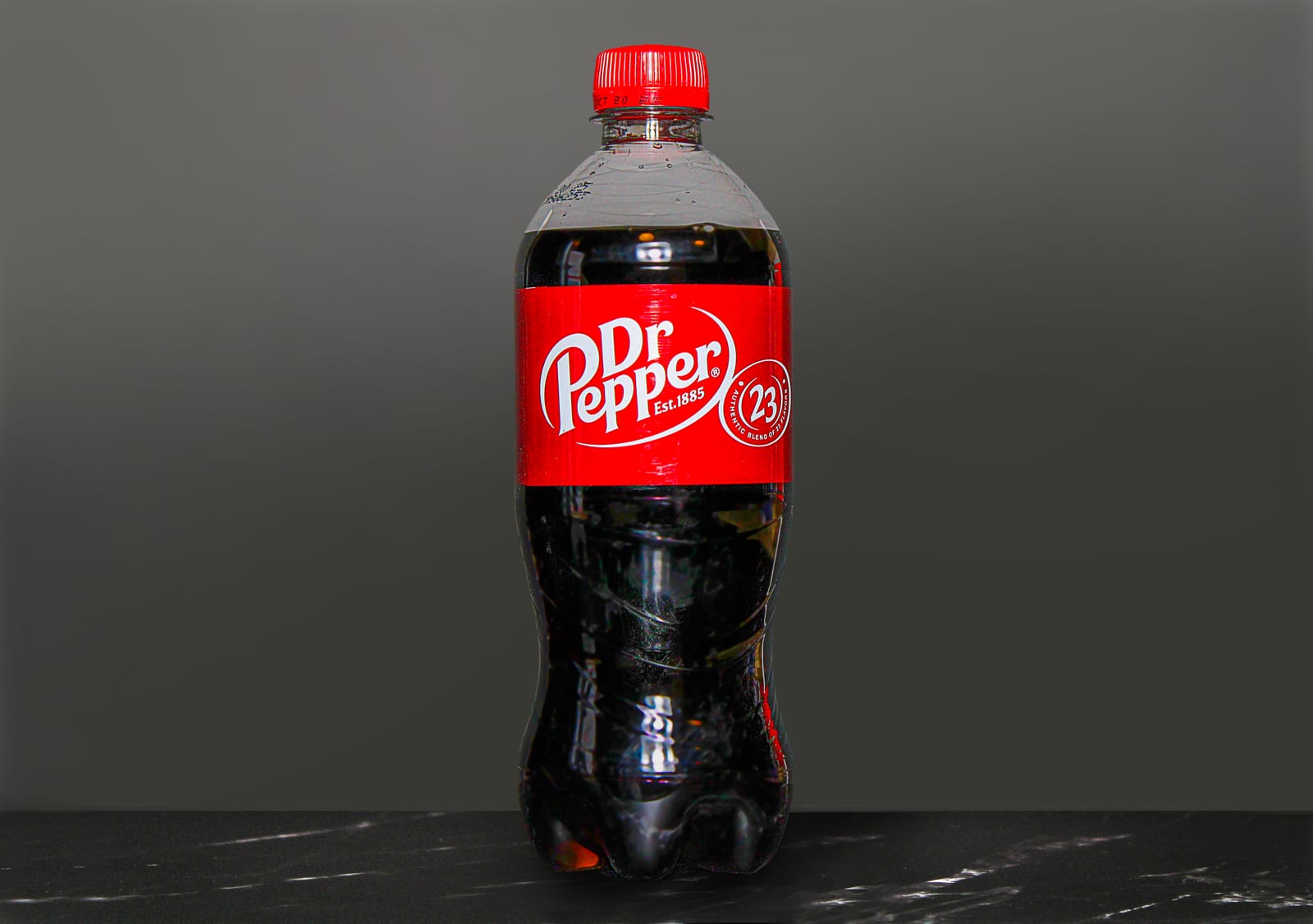 A bottle of Dr Pepper centered against a dark gray background.