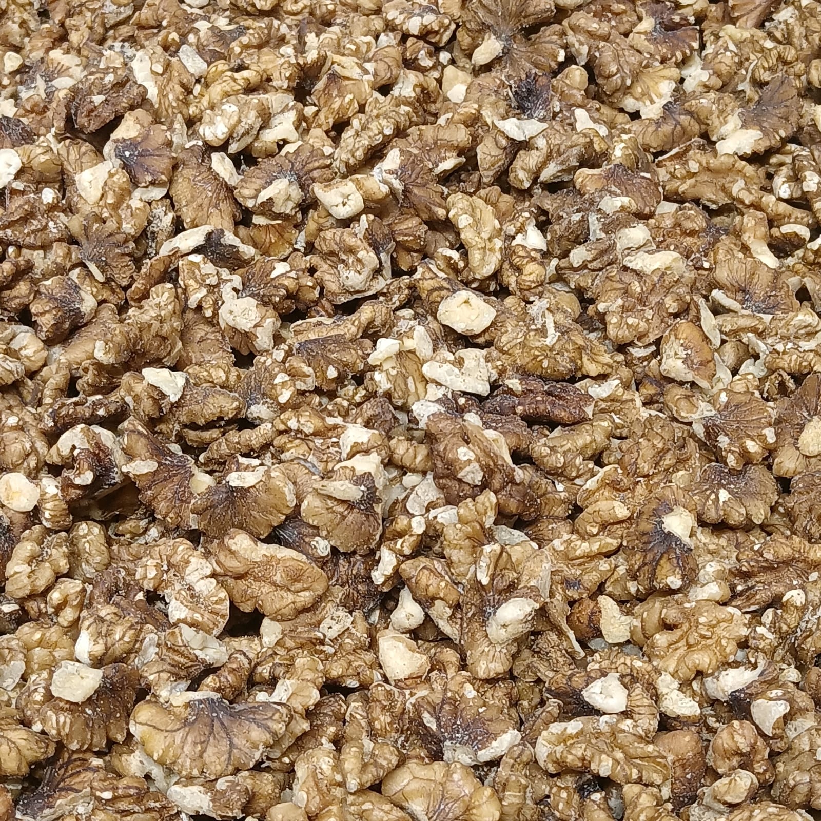 A close view of pale and brown walnut kernels filling the frame.