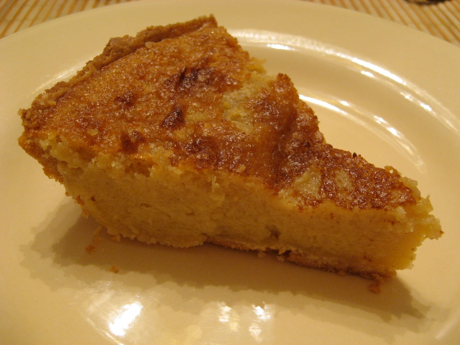 A slice of buttermilk chess pie on a plate beside the remaining pie.