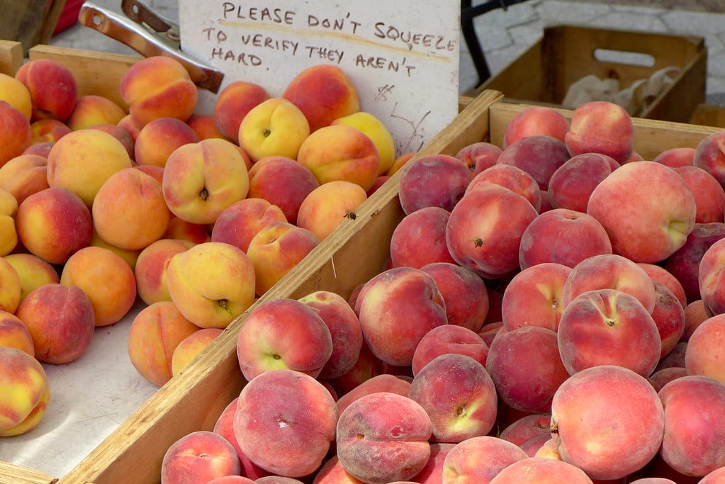 Crates of ripe yellow and red peaches at a farmers market.