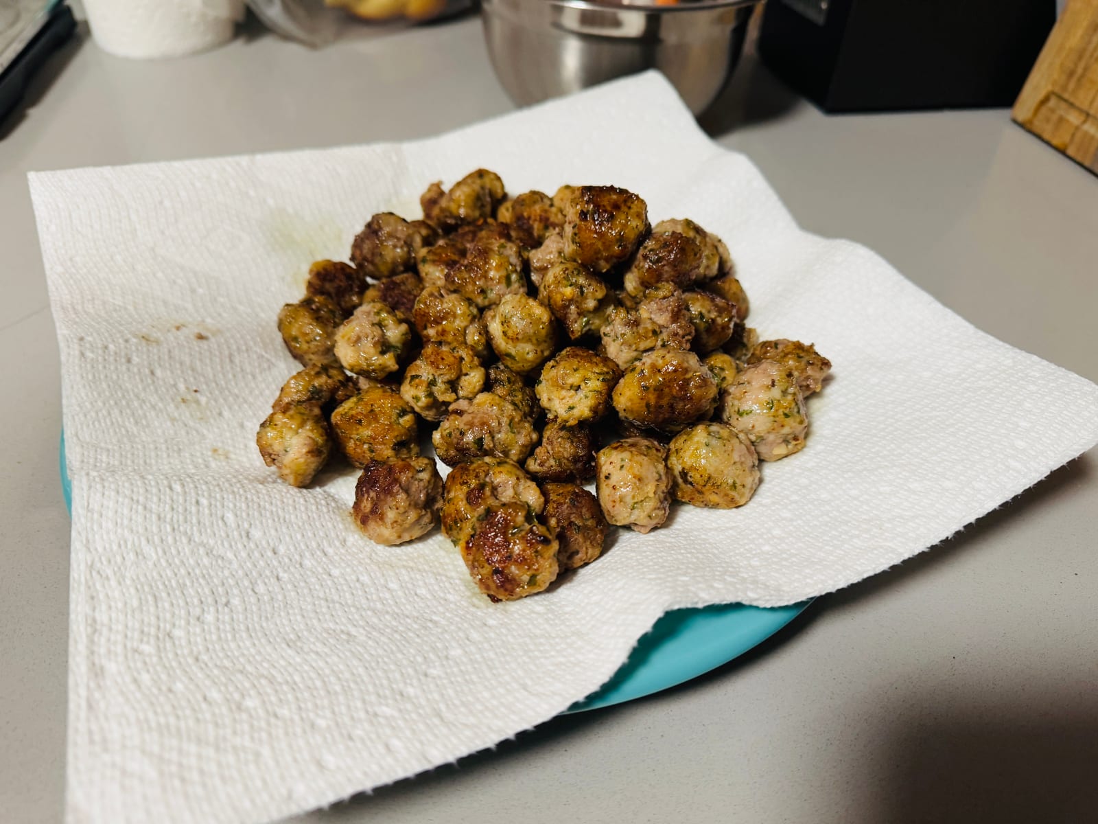 A pile of small browned beef-and-pork meatballs resting on white paper towels.