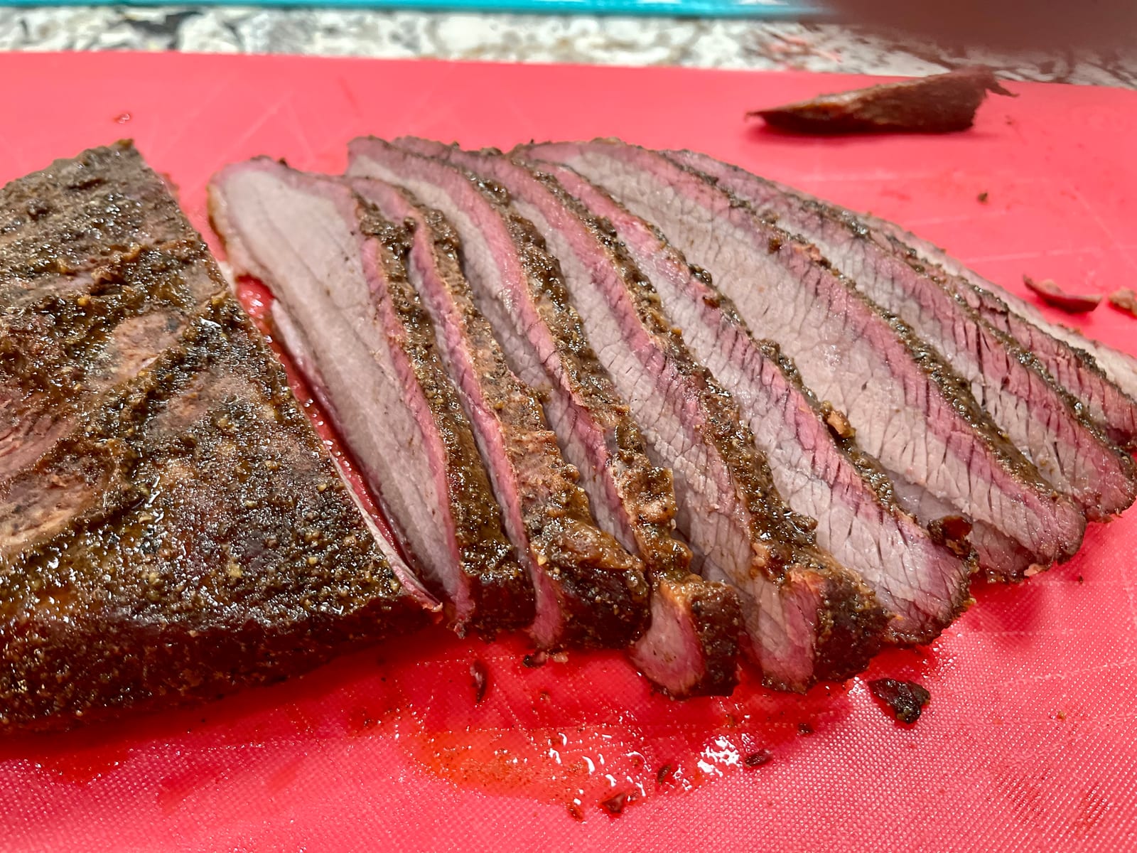 Freshly sliced smoked brisket showing a dark bark and a pink smoke ring.