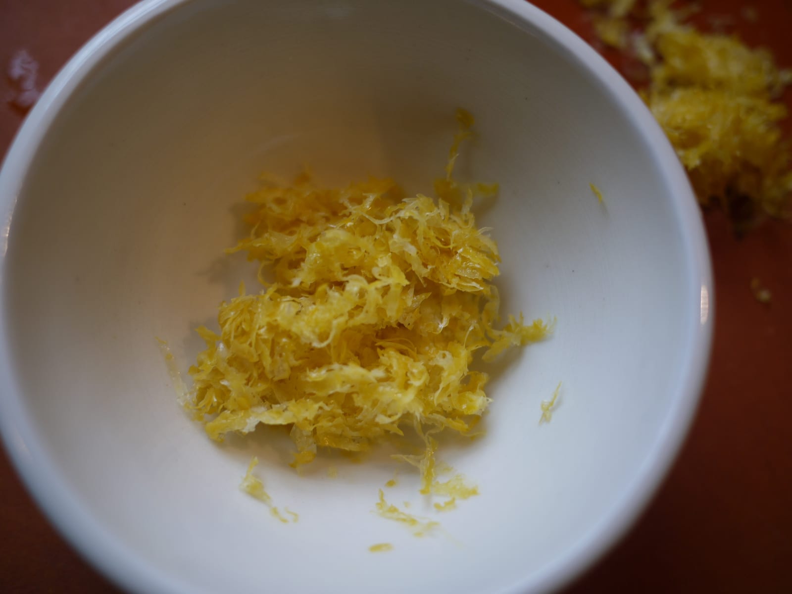 Fresh yellow lemon zest gathered in a small white bowl.
