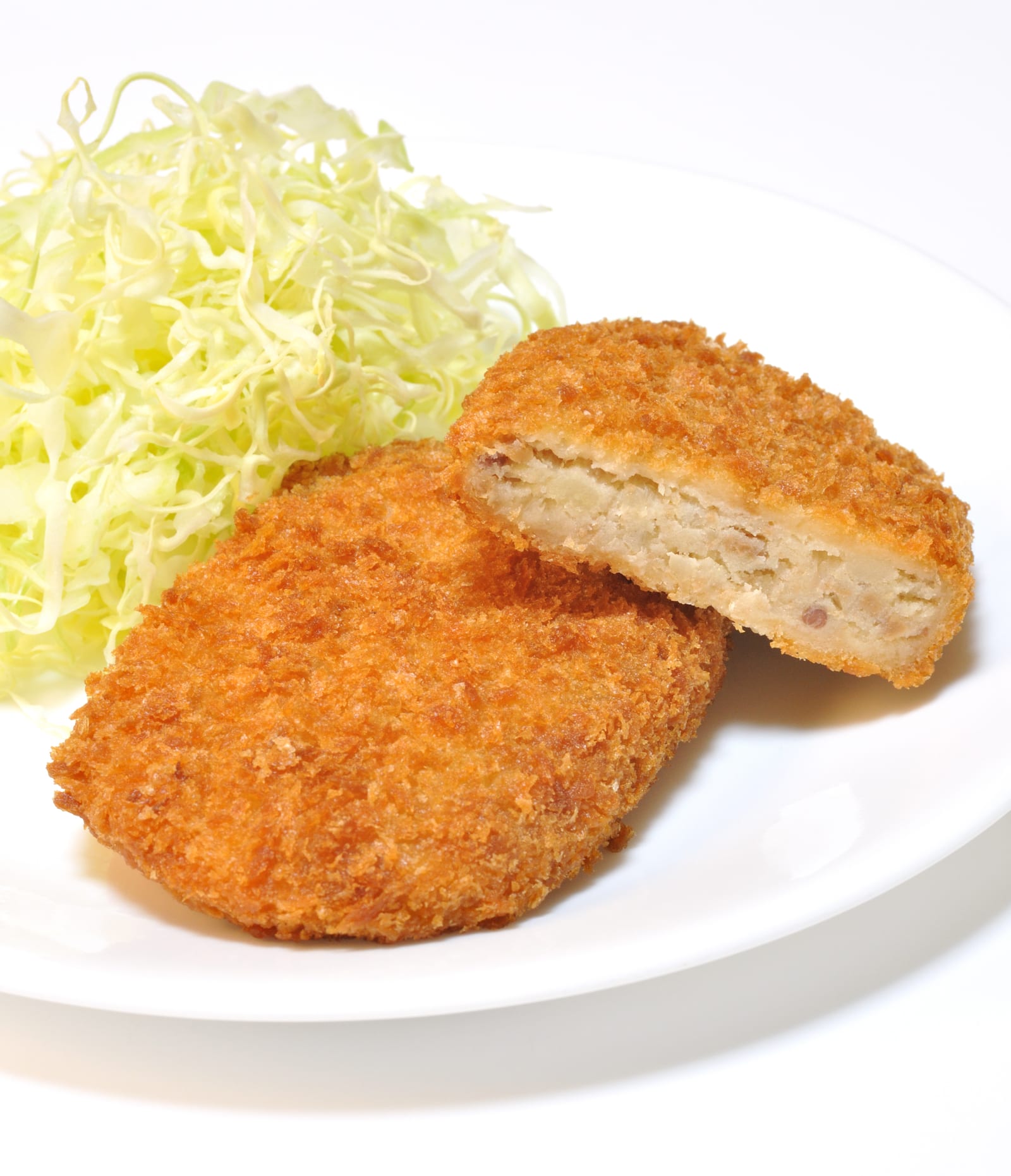 Breaded potato croquettes, one cut open to reveal its pale mashed-potato center.