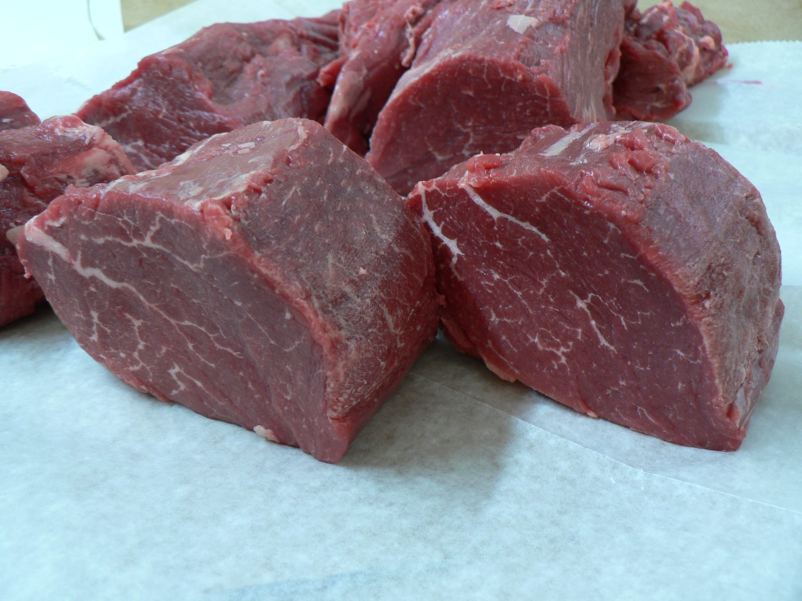 Raw beef tenderloin portions arranged on butcher paper.