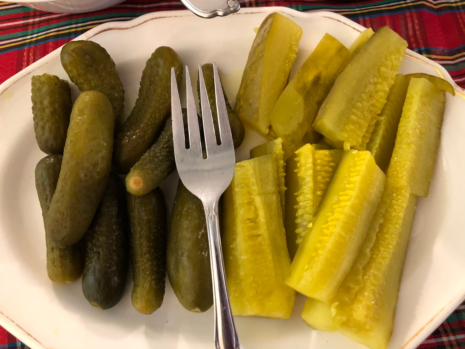 A divided plate with small whole sweet pickles on the left and long dill pickle spears on the right.