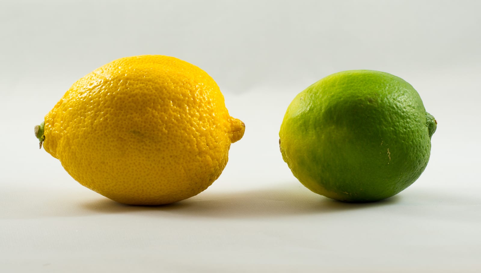 A lemon and lime photographed on a dark surface.