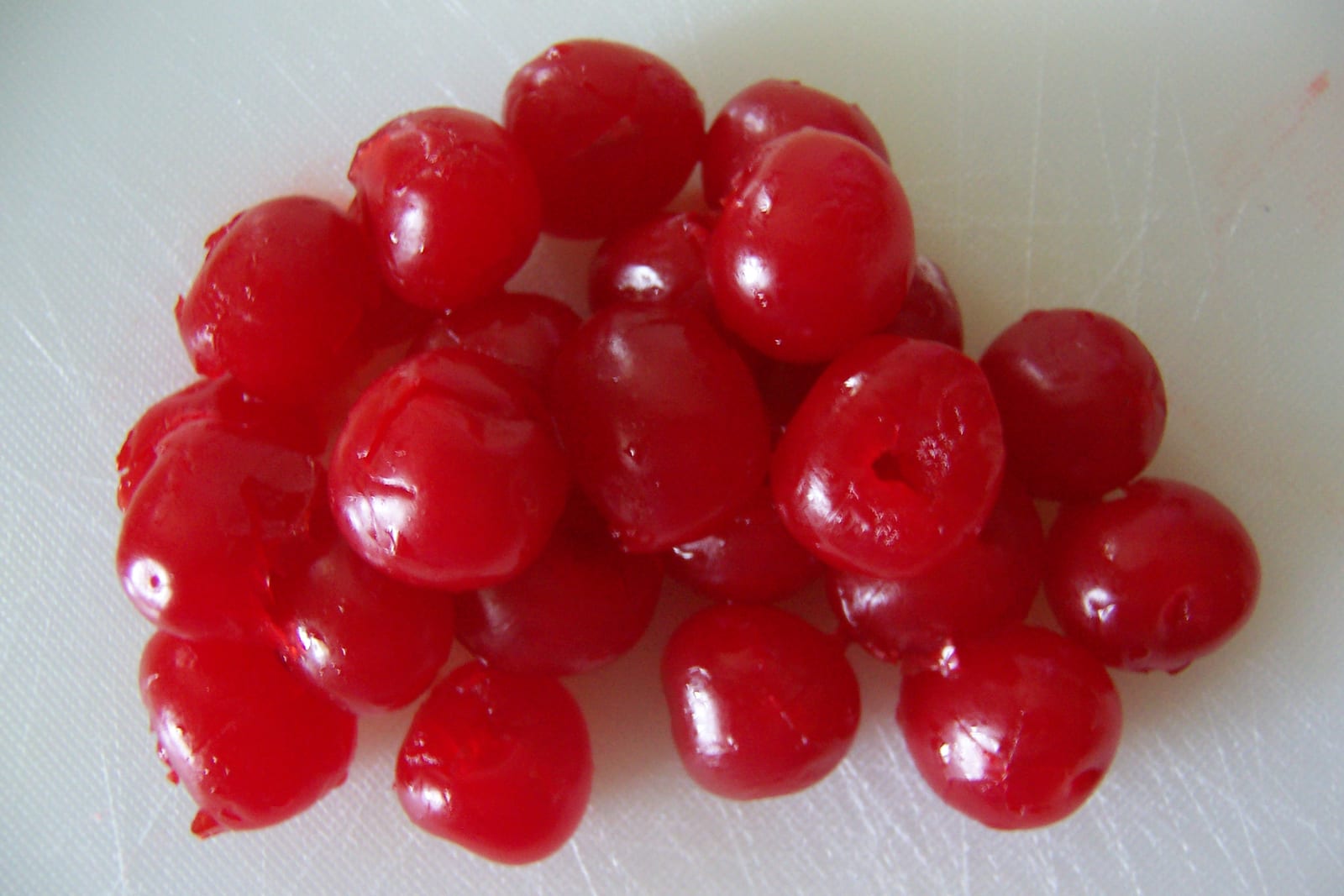Glossy bright-red maraschino cherries piled in a small glass bowl.