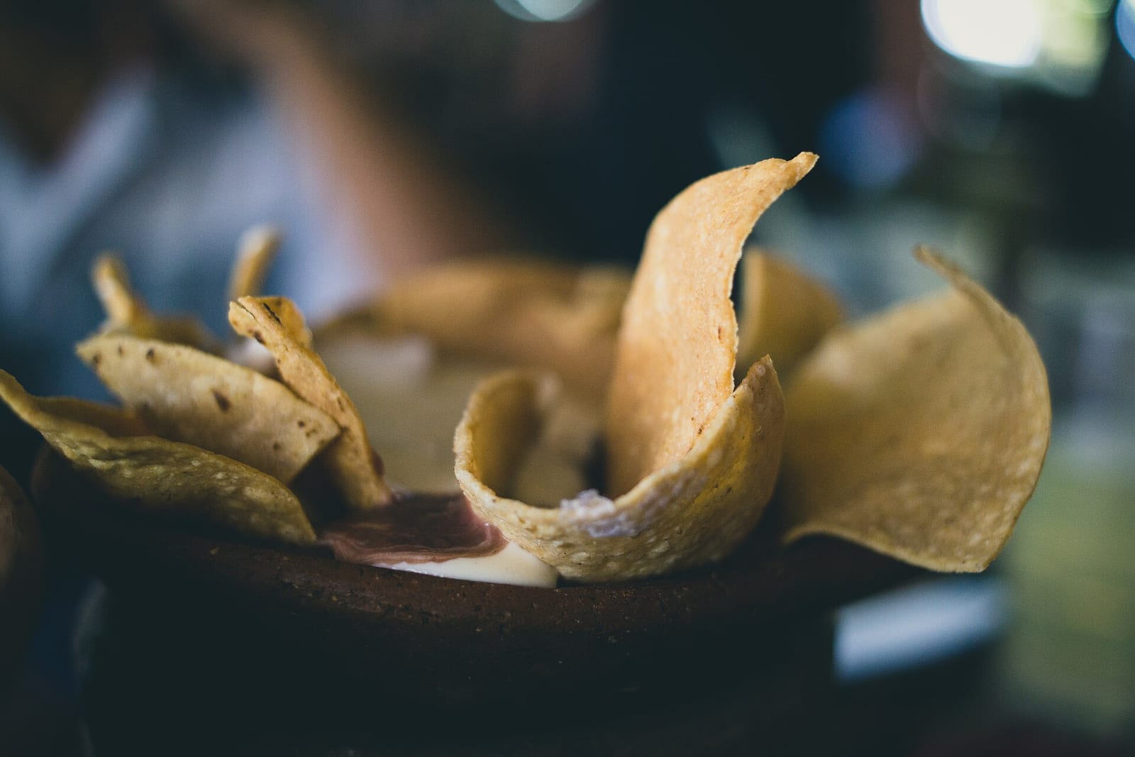 Curved tortilla chips standing upright in a dark clay pot.