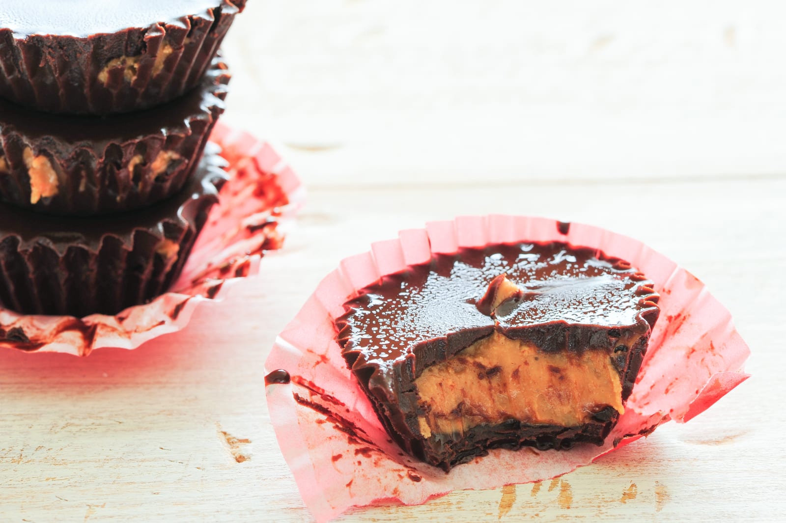 Homemade chocolate peanut butter cups with one cut open to reveal the filling.