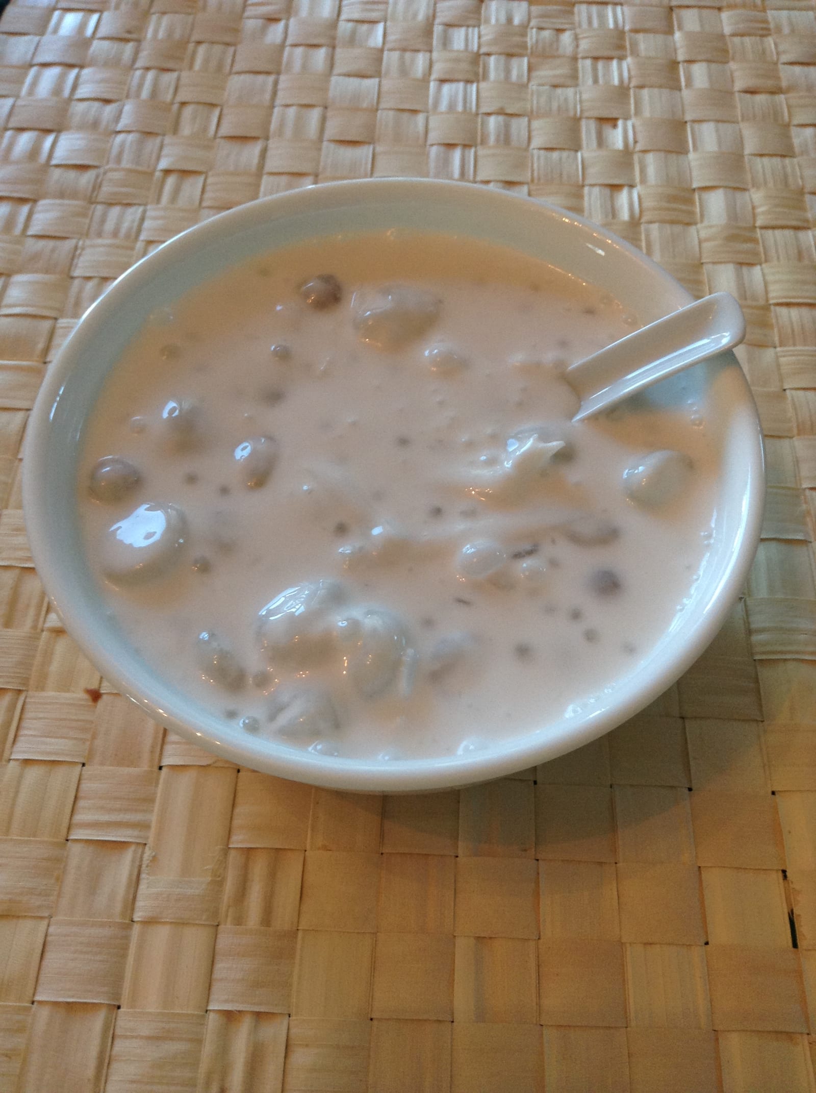 A close view of ginataang bilo-bilo in a white bowl with purple and white rice balls.