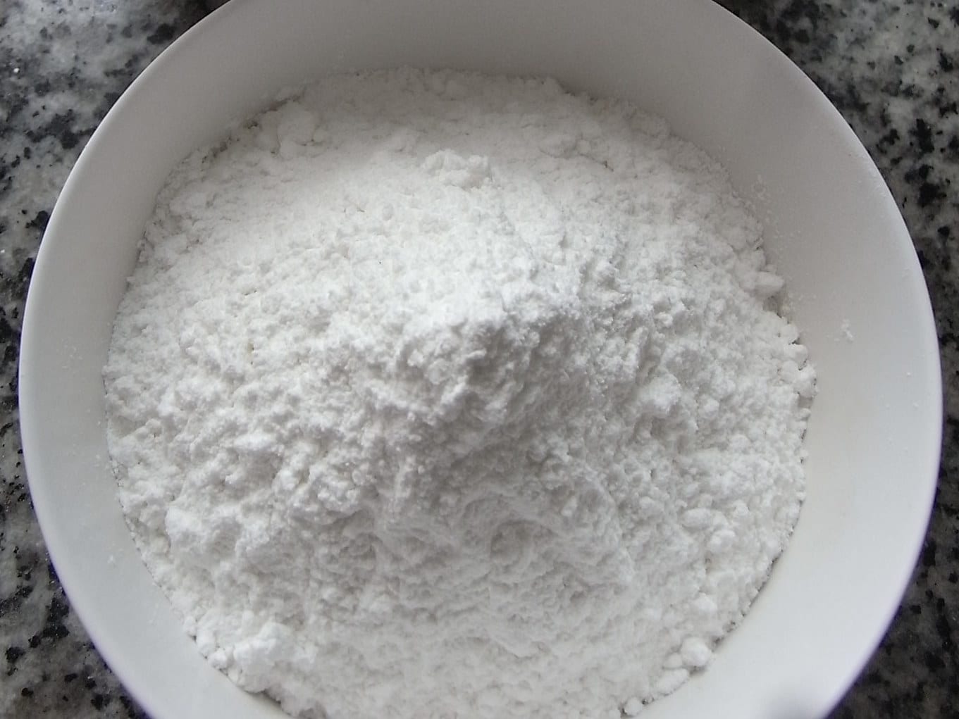 Fine white glutinous rice flour in a clear measuring bowl.