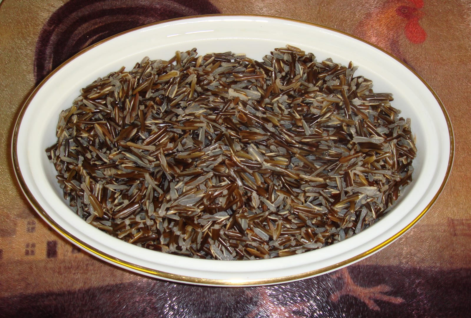 Cooked long dark wild-rice grains and lighter rice grains in an oval white dish.