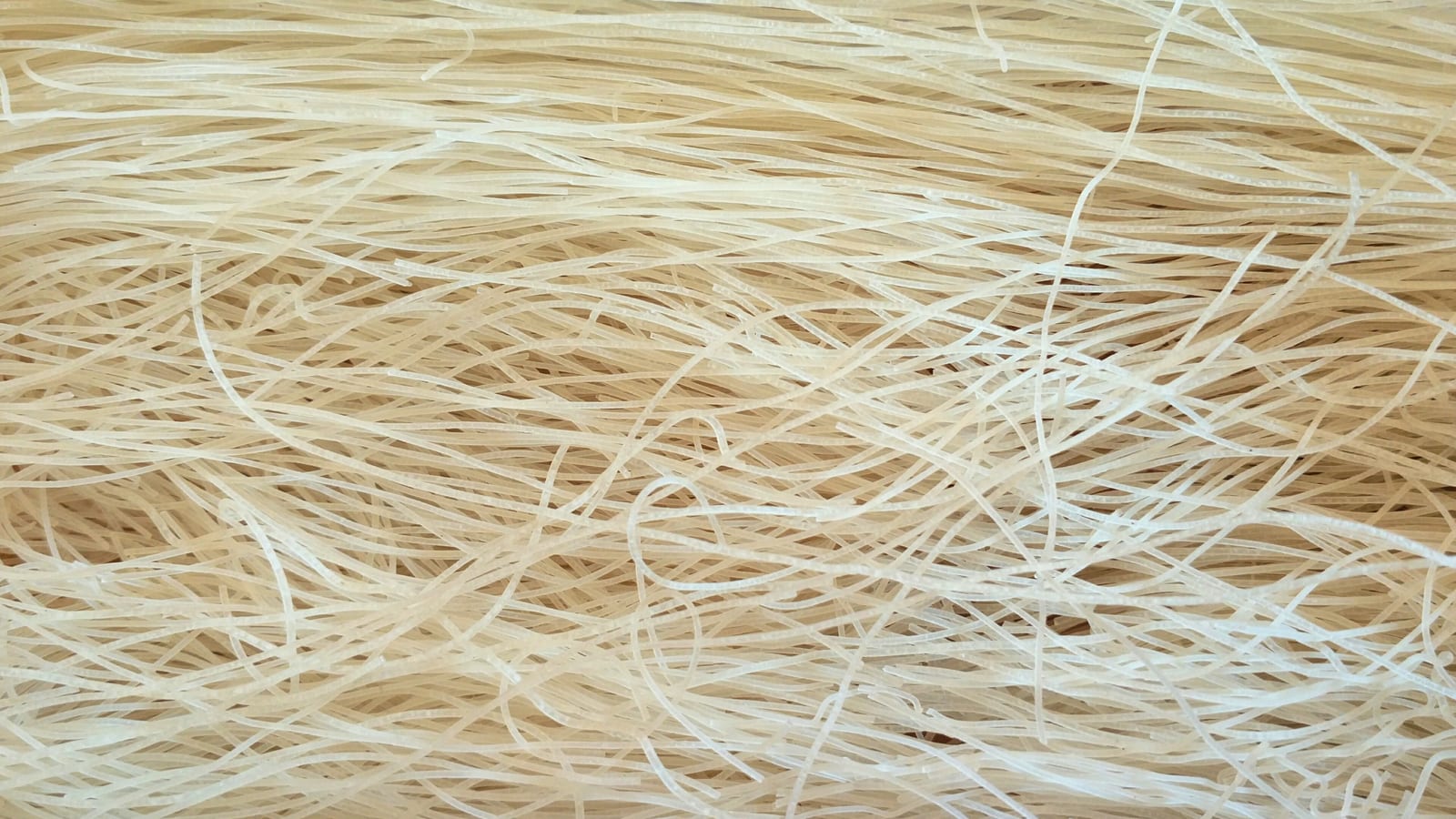 Close view of tangled dry translucent rice vermicelli strands.